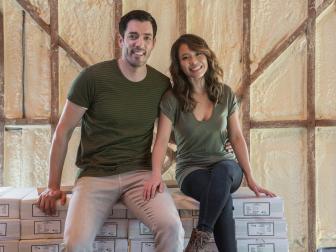 Host Drew Scott and fiancee Linda Phan seat on boxes of new flooring as they check construction progress in their new home, as seen on Property Brothers at Home: Drew’s Honeymoon House.