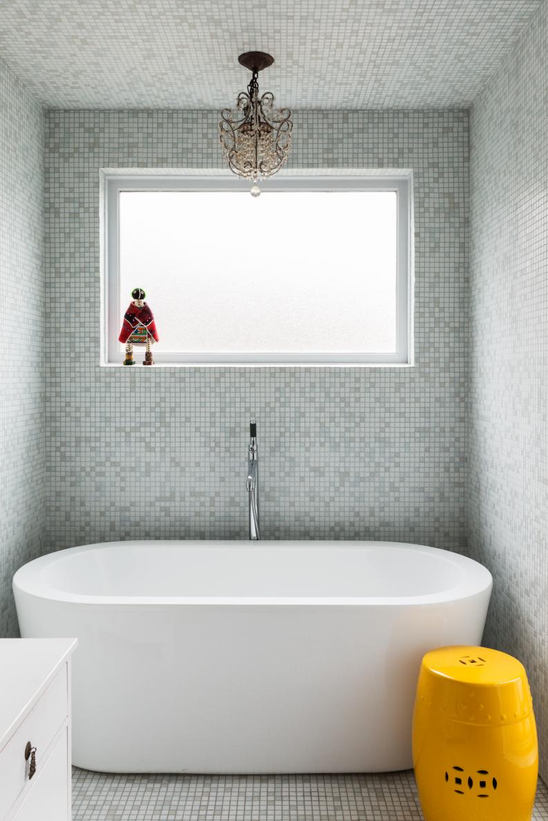 The last little bit of island luxury in this home: a tub fit for royalty. With its bright yellow stool and a petite yet regal looking chandelier, this bath is exactly what anyone would want to soak in after a long day. Surrounded by miniature tile in a calming blue, this Brooklyn bathroom has a definite European vibe.