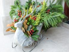 This festive reindeer sleigh is an exercise in abundance, with various types of greenery from lemon cypress to magnolia leaves and berries mixed in to this colorful but still naturalistic arrangement.