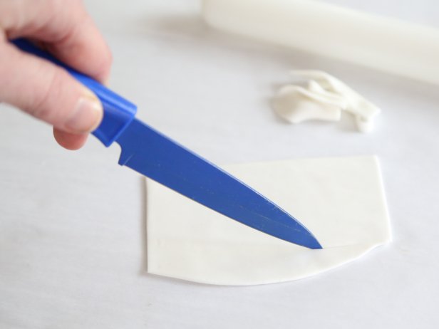 Trim the edges of the fondant edges so they are square.  Cut the fondant piece into long thin strips so they look like fortunes. Let stand until the surface is dry, about 1 hour.