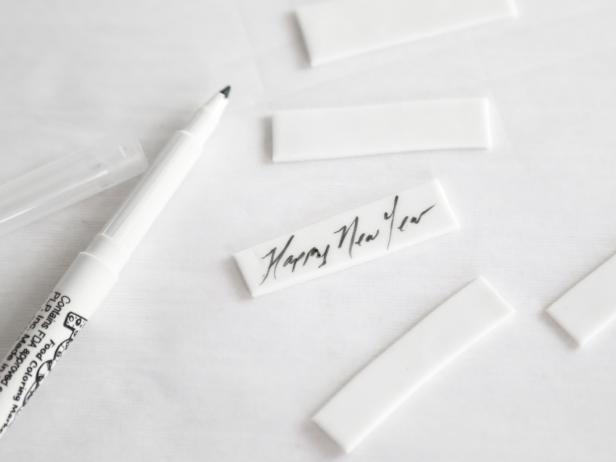 Use a food writer to pen “Happy New Year” and other messages on the fondant strips. 