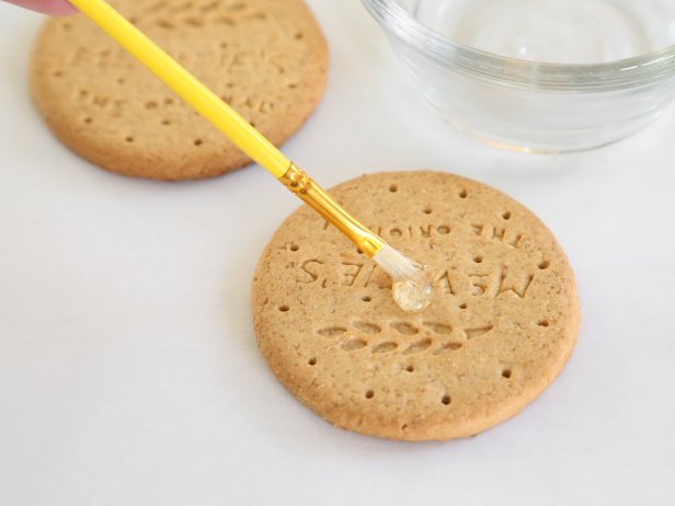 Use a small paintbrush to dot corn syrup on top of the cookies.