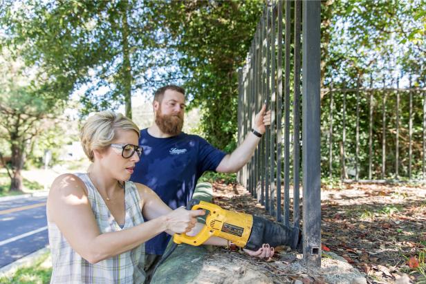 As seen on Home Town, Ben (C) and Erin Napier (L) work on the wrought iron fencing in the front of the Walker residence.  They are using a sawzall to remove the center sections of the fence to give the front of the house a more open feeling. Ben and Erin Napier are renovating this house for the Walker family. (demolition)