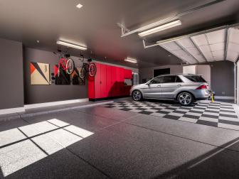 Garage features gray cement-speckled floors with carpet tiles
