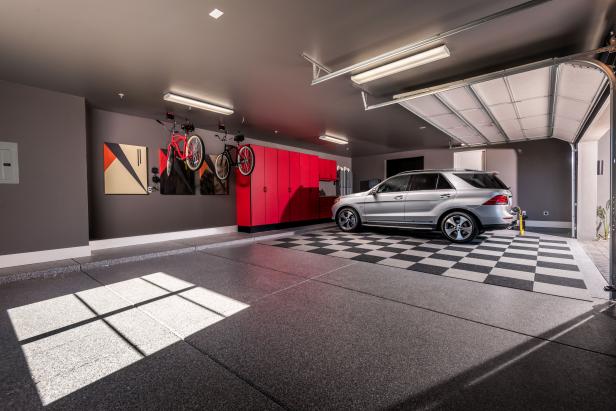 Garage features gray cement-speckled floors with carpet tiles