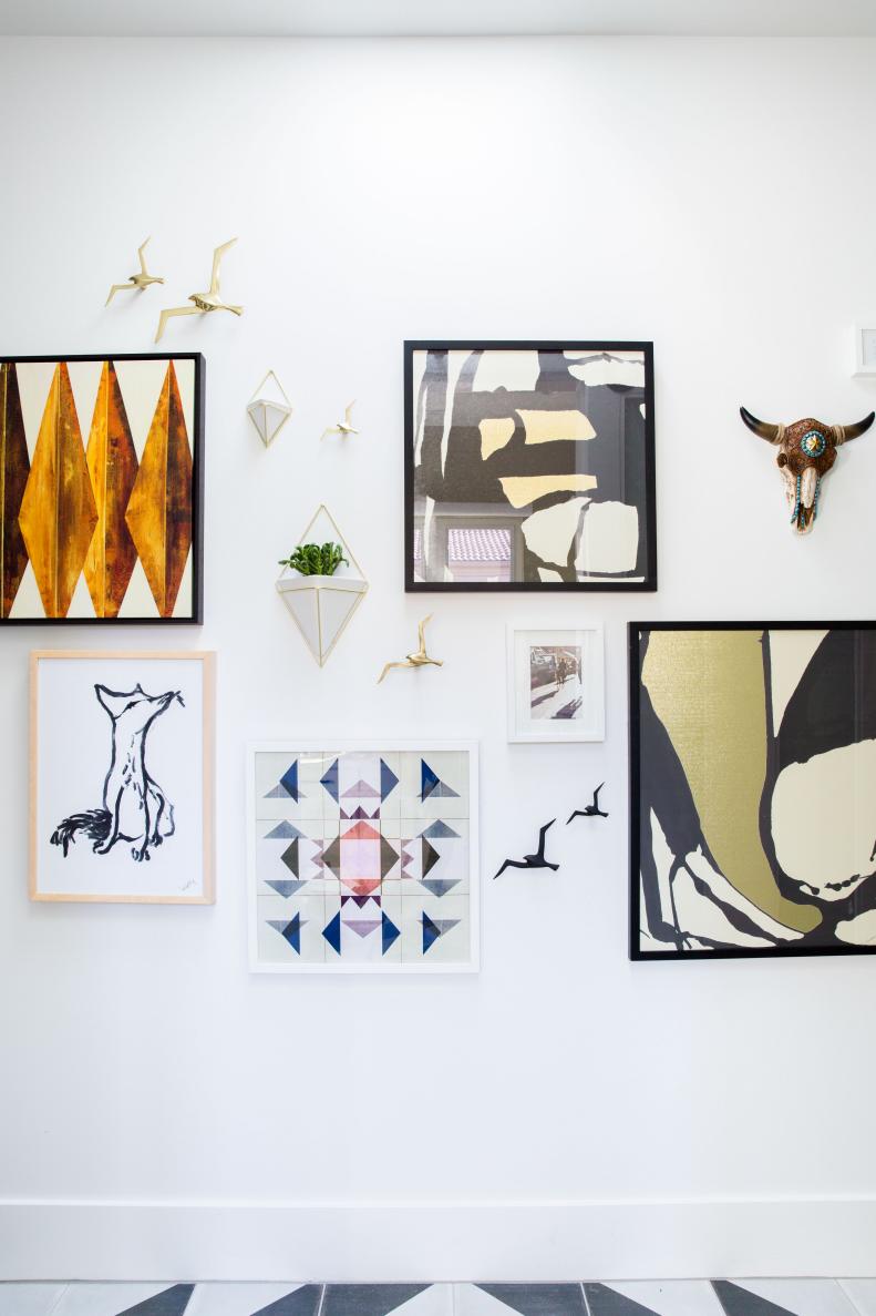 Hallway gallery wall mixes traditional art with digital canvases
