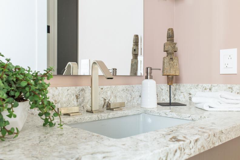 Powder room vanity has gray sink and widespread brushed nickel faucet