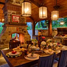 Lavish Covered Patio Featuring Dining Set Up, Grill and Stone Fireplace 