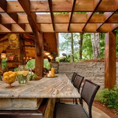 Pergola Covered Outdoor Stone Countertop Bar Seating With Wicker Chairs and Natural Rock Structures 