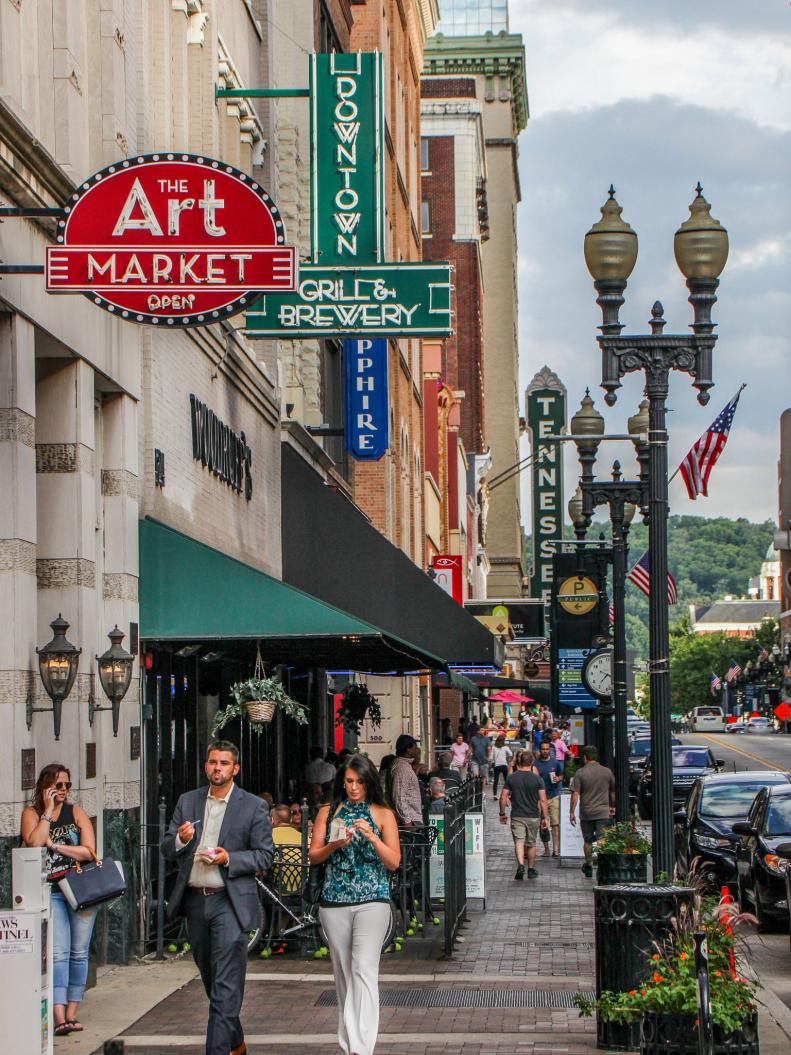 a bustling city street with businesses, restaurants and bars