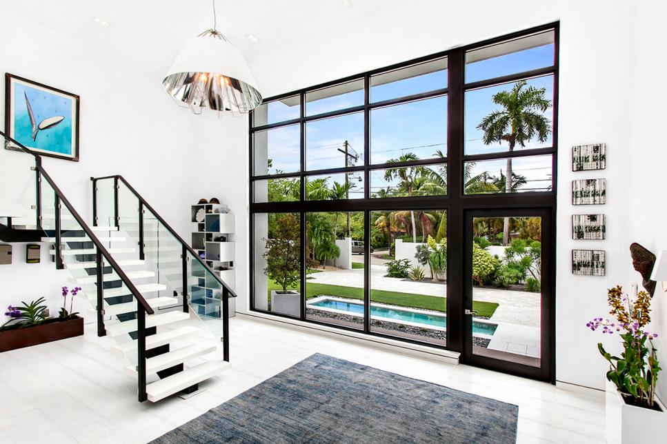 Striking Modern Entryway in White with Clear Glass Stair Railing