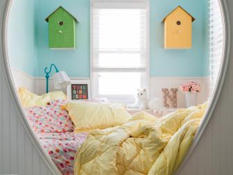 Create a special spot for little ones to sleep with a headboard cutout nook. This was made by framing in a full size bed with basic lumber, then creating a whimsical wall with tongue and groove bead board, caulk and glossy white paint. For an extra element of fun, wooden birdhouses were updated with decorative paper and outfitted with simple lighting kits for use as sleepy time sconces.