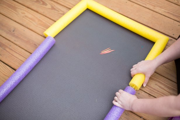 To complete the lanes, attach an uncut pool noodle of a different color to each side using toothpicks (Image B ). For a more permanent alley, use duct tape to secure the noodle joints. Lay the assembled noodles on top of your yoga mat, set up the pins, and bowl!