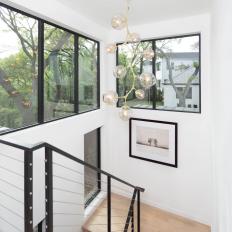 Light and Bright Staircase With Natural Hardwood Floors and Contemporary Chandelier 