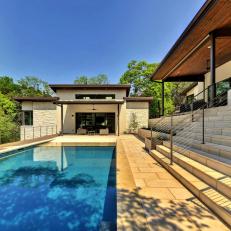 Contemporary Pool With a Neutral Stone Poolhouse and Shaded Outdoor Space