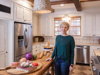 As seen on Home Town, host Erin Napier (C) stands in the newly renovated kitchen. After the renovations, the Carson's Laurel, MS kitchen now features a completely renovated French Country styled kitchen with new distressed cabinet doors, new appliances, new floor and wall tile, new heart pine reclaimed beams and a custom built Scotsman white oak table built by host Ben Napier. (portrait)