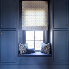 Blue Country Window Seat With White Roman Shade, Striped Seat Cushion and Patterned Pillows