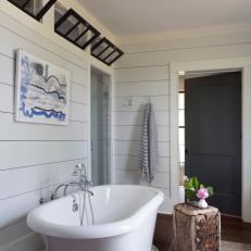 White Shiplap Country Bathroom With Bathtub and Natural Wood Table  