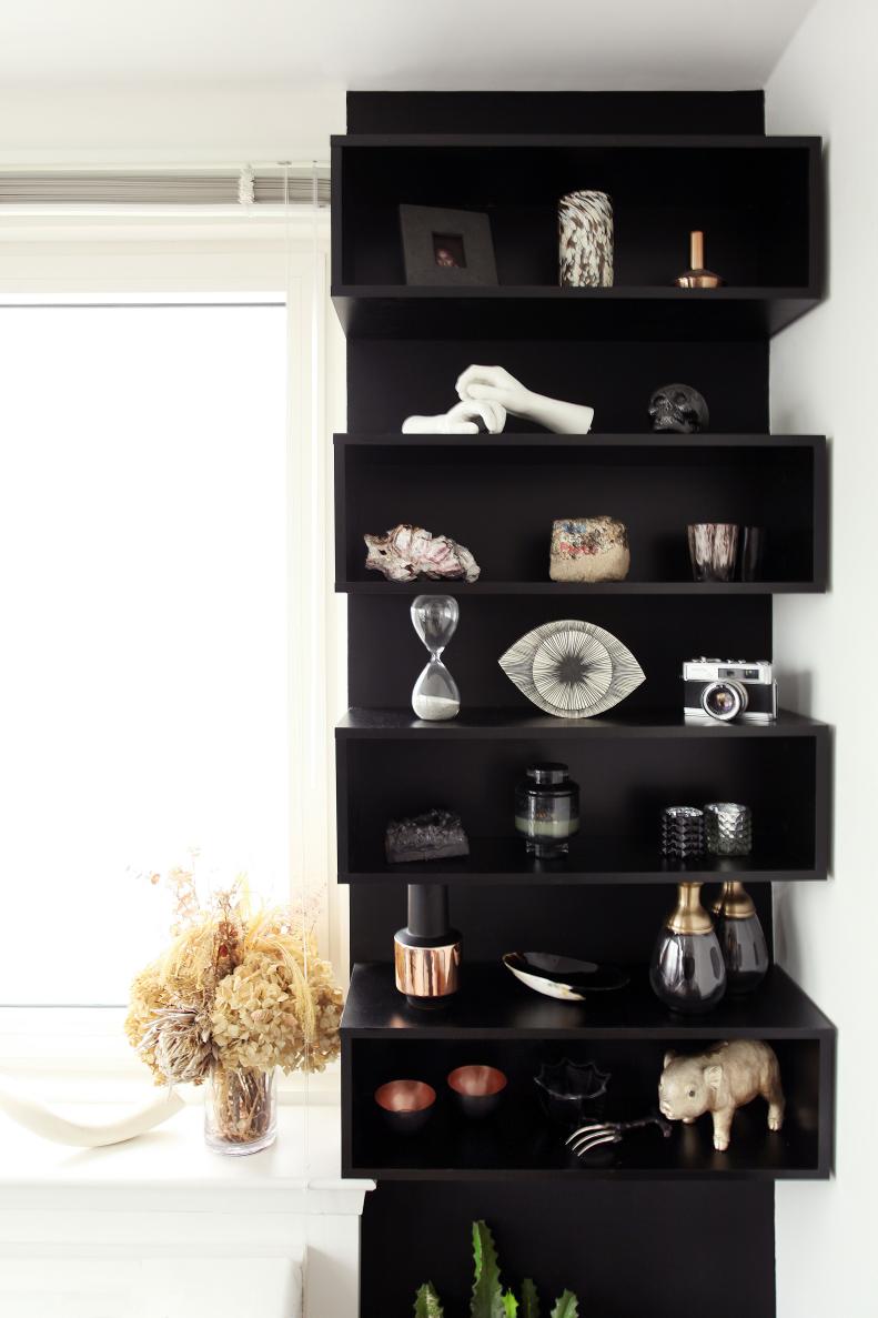 Storage is key in every home as is a good dose of creativity. This built-in bookshelf was a DIY project by the couple to create an architectural feature in the home. The finished product was painted black to add a touch of sophistication and contrast to the shelves which hold a fun assortment of small accessories and pieces picked up on travels in Paris, the Netherlands and Japan.
