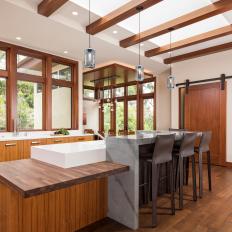 Warm Wood Kitchen With Thick Window Frames, Marble Island Accent and Skylight Beams