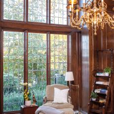 Victorian Sitting Room Featuring a Brass Chandelier, Large Arched Window and Plush Beige Chair