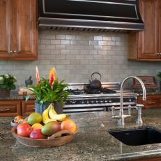Traditional Kitchen Featuring Rich Wood Cabinetry, Gray Tile Backsplash and Green Granite Countertop