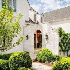 White Home Exterior With Landscaping and Brick Archway