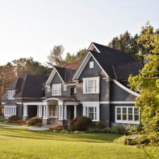 Tudor-Style Home Covered in Gray Shingles With Copper Roof