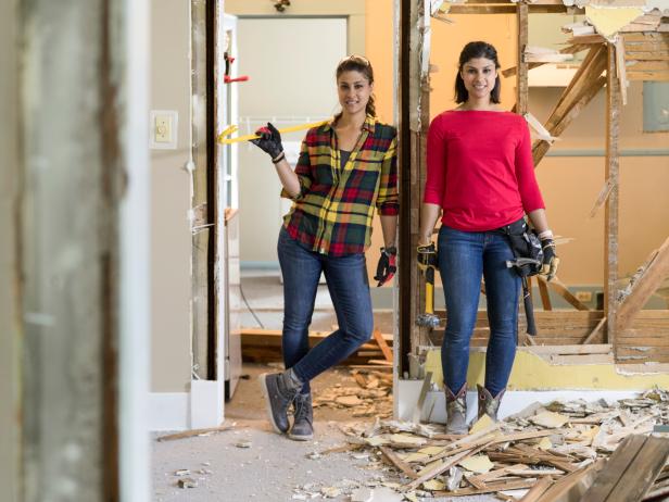 Hosts Lex and Alana LeBlanc pose in the newly demolished doorway between the living room and kitchen of Kurt and Emma's home, as seen on Listed Sisters.
