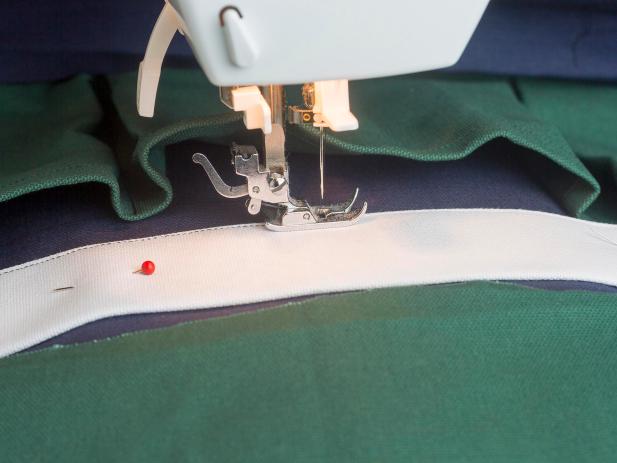Sew a seam along the long, open edge, very close to the edge. Center this piece between the bottom of the second cushion and the top of the pockets, inserting the sides under the fold of the base fabric. Pin and sew in place on all edges.