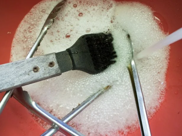 Cleaning dirty grilling utensils.