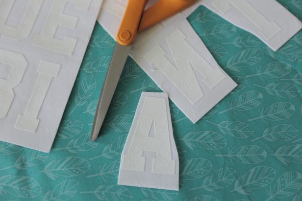 Using your scissors, cut out all the letters needed to spell the top line. We went with 3-inch tall letters for eye pleasing scale. Make sure to leave about an 1/8 of an inch of the transfer paper around the actual letter so you have an edge to peel up in later steps.