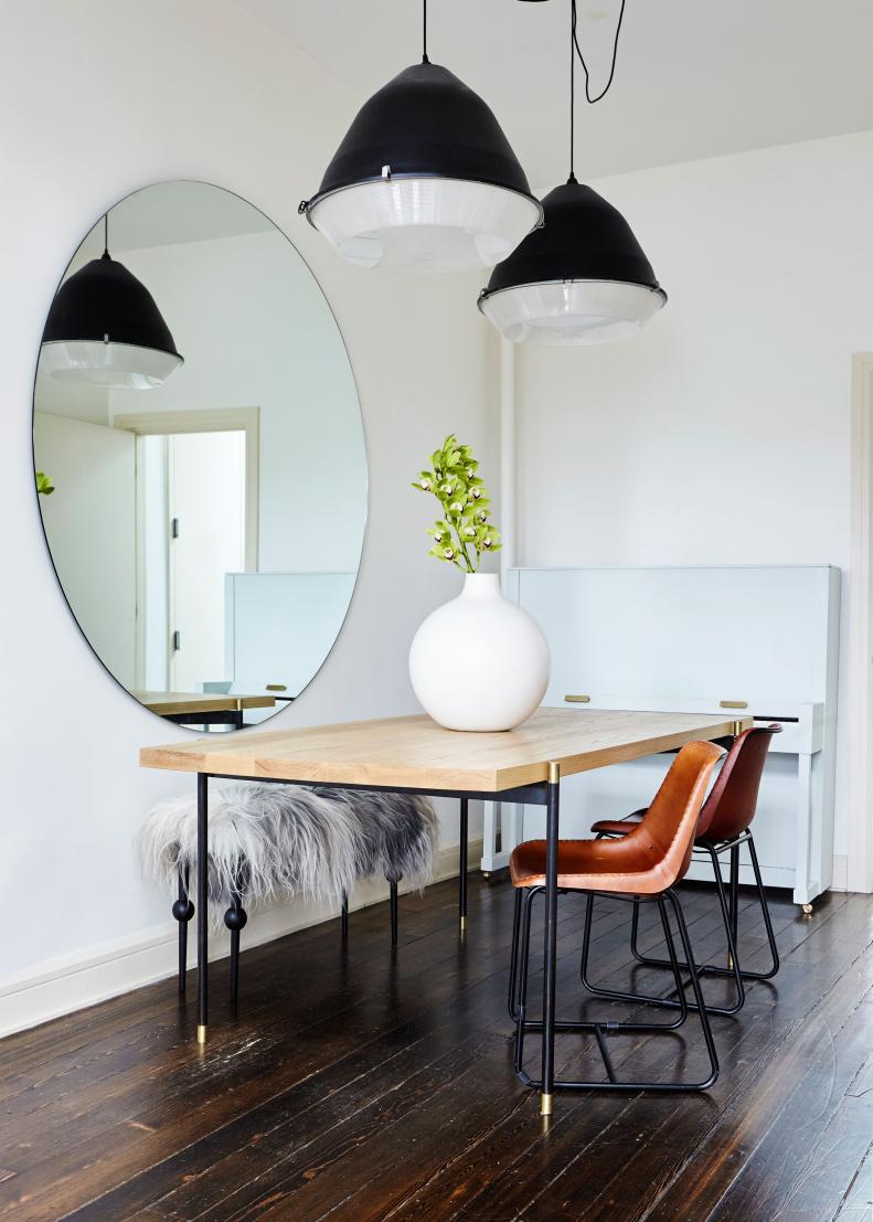 The dining room is a study in minimalism. What makes the aesthetic work are the layers of texture and finishes that keep the eye delighted. In this dining room wood meets iron, meets brass, meets leather, meets sheepskin for a perfectly layered affair. Above the dining table, another piece designed by the couple, vintage lighting that can be found in industrial buildings, was installed. The found pieces were upcycled with the addition of black paint. 

