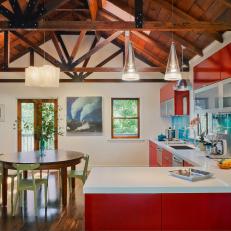 Open-Plan Kitchen With Exposed Rafters and Red Cabinets