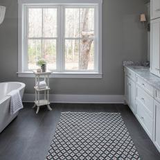 Bathroom With White Tub, Gray Tile Floor & Marble Countertop