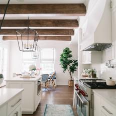 Two White Kitchen Islands Under Exposed-Beam Ceiling