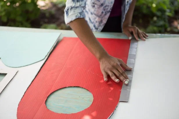 hands pressing down red cardboard peice