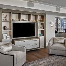Contemporary Living Room With Neutral Velvet Chairs and Large Entertainment Center