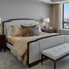 Neutral Master Bedroom Featuring Upholstered Bed, Matching Nightstands and Gold Bed Linens