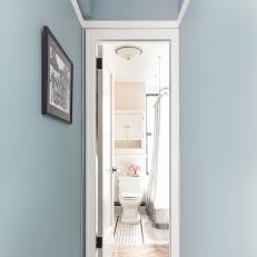 Light Blue Hallway Leads to Neutral Bathroom