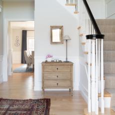 White Foyer With Dresser, Rug and Staircase With Spindles