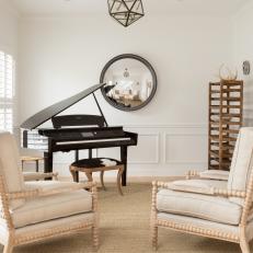 Piano Room With Round Mirror and White Chairs