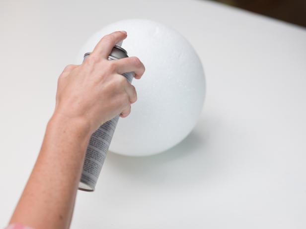 Set the medium or large Styrofoam ball on top of a sturdy surface. Use craft paper or a painters drop cloth underneath the Styrofoam balls before painting to protect your surface.  Completely cover the Styrofoam ball with the black spray paint.  Immediately after spray painting the Styrofoam ball while it is still wet pour on the black glitter, let dry.
