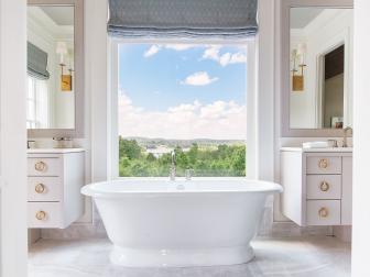 Can you imagine taking a bath in front of a view like this? Angela Blehm's master bath is the definition of relaxed elegance. The overall palette of her home is so incredibly colorful and vibrant, that the master bath's classic design makes for the perfect sanctuary. Angela achieved a cohesive look within the space by repeating the Benjamin Moore, Cumulous Cloud, wall color on their custom vanities and adding the gorgeous "York" bathtub from Victoria + Albert. My favorite detail about this space is the repetition and balance of simple shapes. Brass sconces and round pulls are the perfect finishing touches.