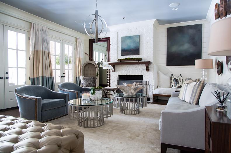 Here in the family room you can see the soft gray-blue palette shared by the majority of the home’s main level. I’m immediately struck with how the simple walls and painted brick allow the artwork to pop off the walls. We didn’t use a lot of pattern in this room. However we created our own with these solid silks, creating a cool color-blocked look for the panels. Just as much work went into choosing the comfortable furniture. I just want to take a seat on that rug!