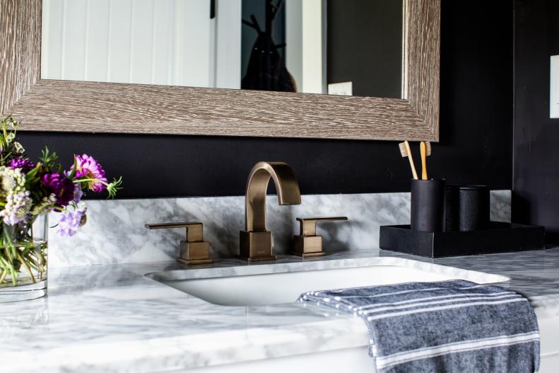 The vanity's beautiful Carrera marble countertop picks up the black and white design details in the powder room, and coordinates with the matte champagne bronze finish on the sink faucet. 