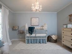Fixer Upper Hosts Chip and Joanna Gaines transformed a depressing room into a bright and festive nursery for the Purks' baby on the way.  The French Doors were removed to create a solid wall for a crib or bed placed against.  The old wall paneling was removed and replaced with light blue painted drywall with white trim.  Soft carpeting will be perfect for a child's room and metal crates hang on the wall and serve as storage for stuffed animals.  A crystal chandelier was removed from the original dining room and installed here in the nursery, as seen on HGTV's Fixer Upper. After #6 (afters)