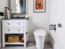 A white wood vanity looks like a piece of furniture in this clean and simple guest bathroom located on the second floor at HGTV Smart Home 2018. 