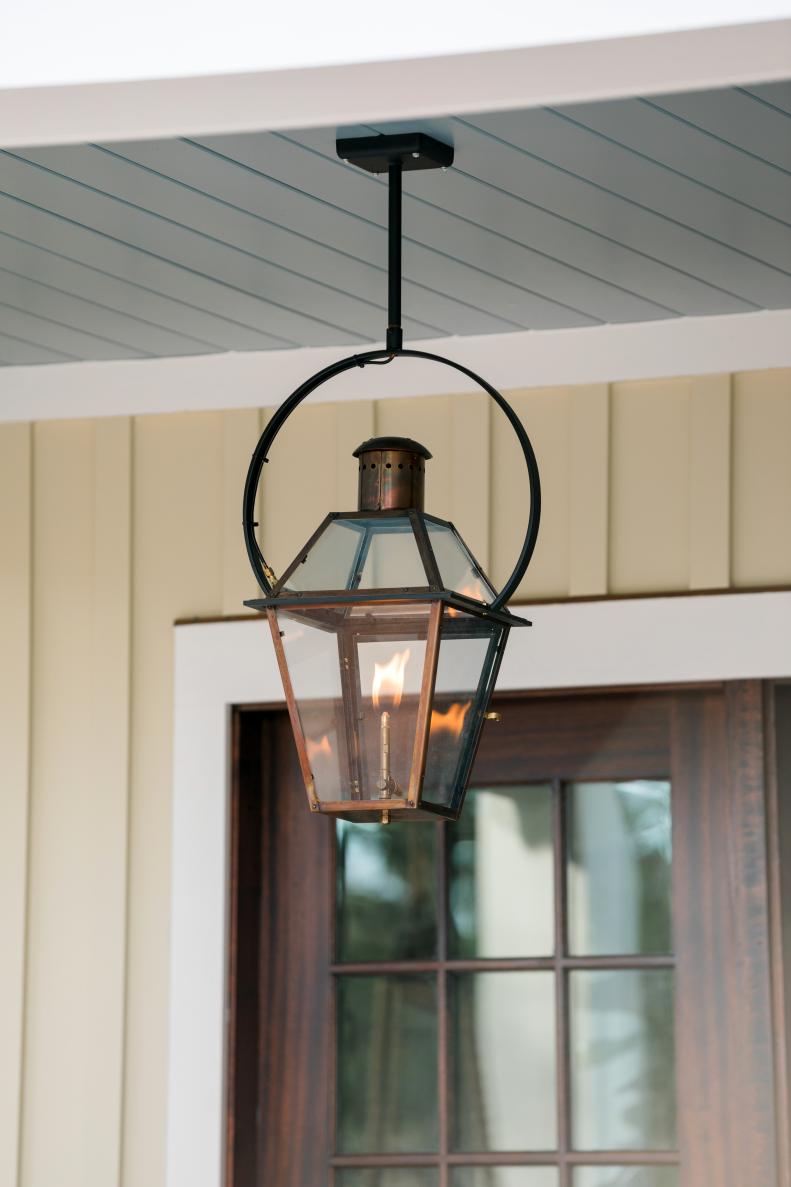 The front porch’s copper gas lantern has a yoke bracket that makes hanging a gas light safe and beautiful. Guests might be surprised to find this home’s front porch has a blue ceiling. “There’s this old wives’ tale in the area that if you paint your ceilings blue, a shade of blue, it will keep spirits away,” says designer Tiffany Brooks. 