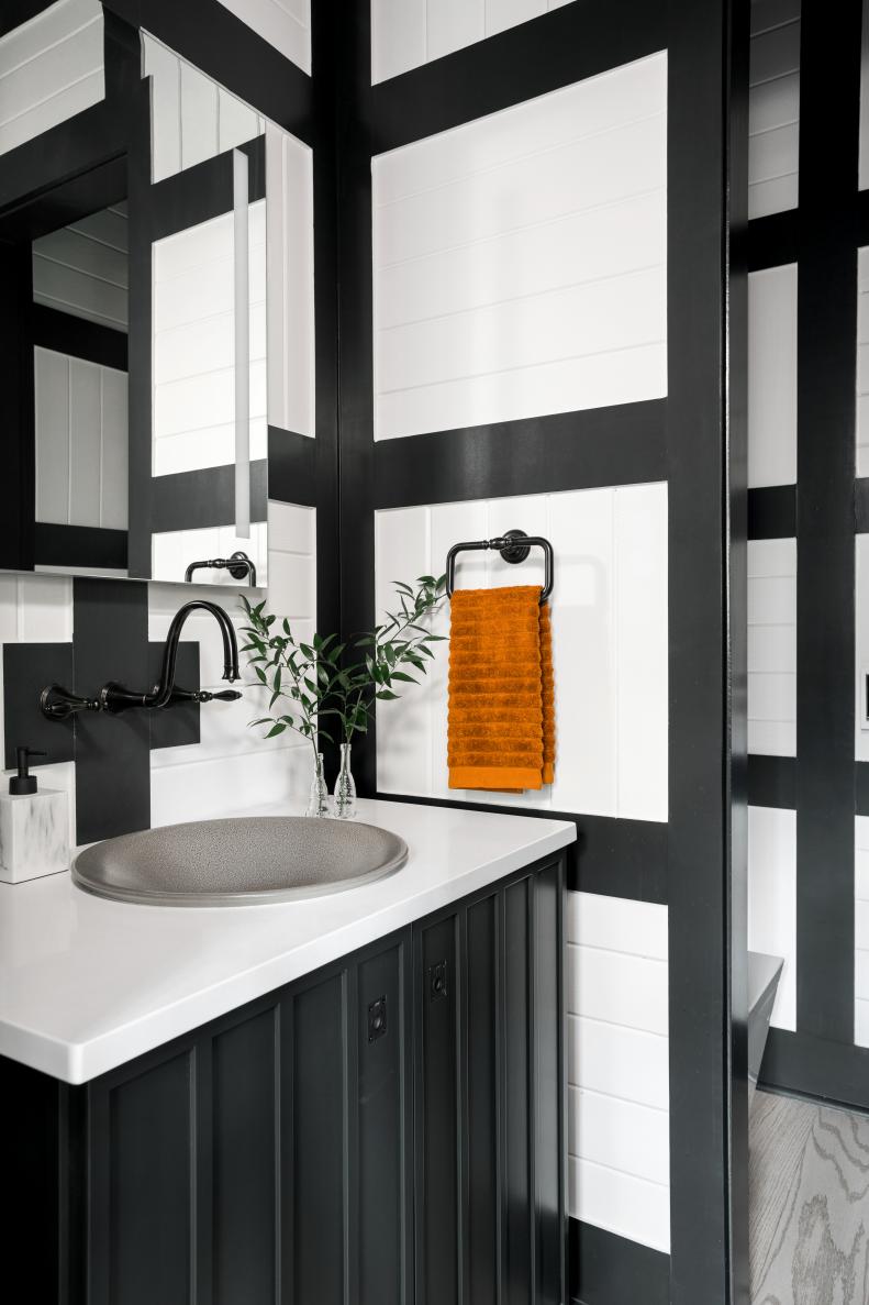 The powder room’s fashionable black vanity has custom doors with inverted paneling and inset hardware. 